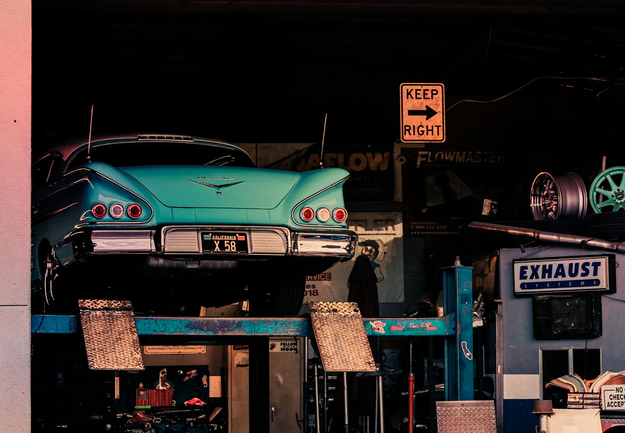 Classic turquoise vintage car elevated on a garage lift, showcasing its retro charm.